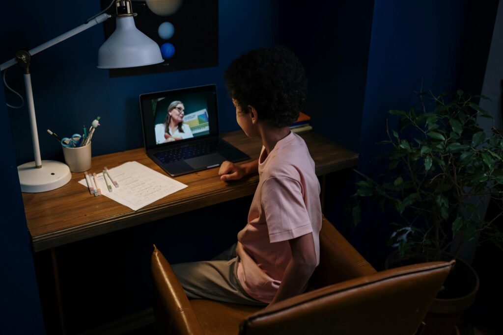A child participating in an online learning session at a home desk with a laptop.
