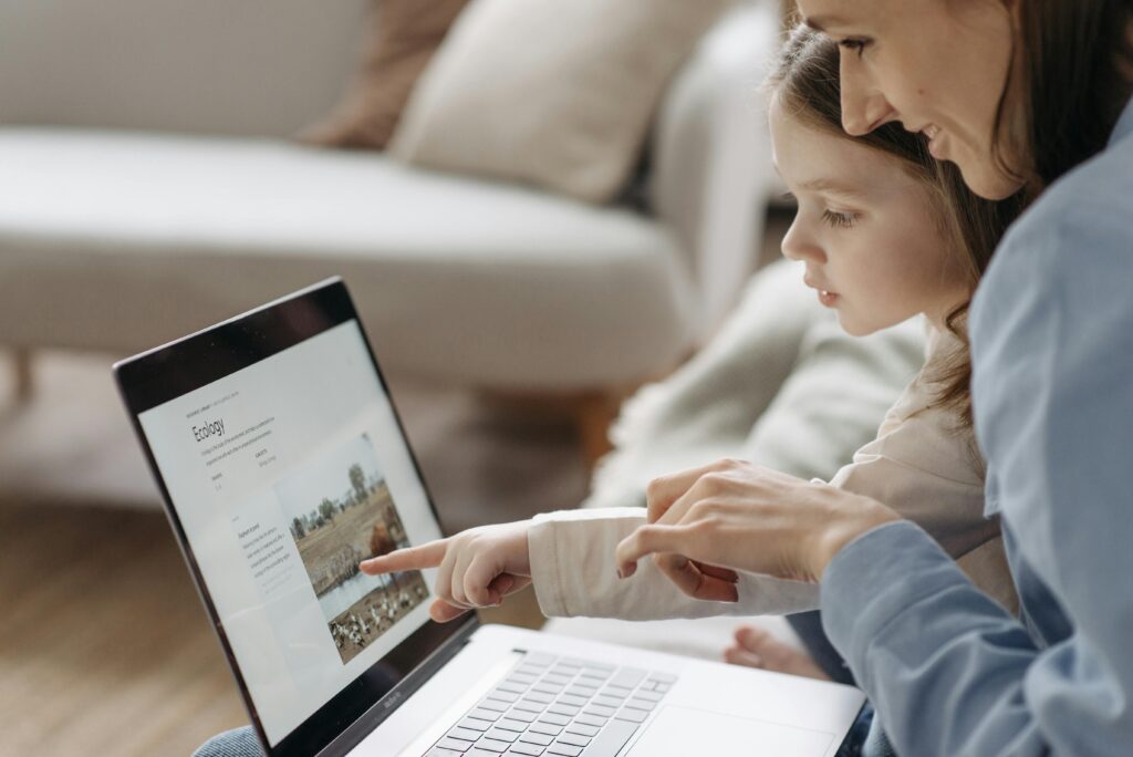 Mother and child exploring educational content on a laptop at home.